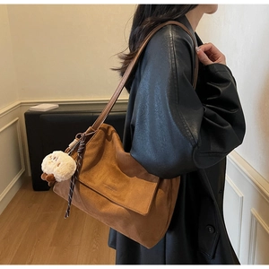 Brown suede tote bag detail with vintage leather embossing and a cute plush bear charm