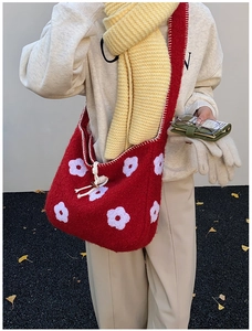 Detailed view of plush red tote bag with flower embroidery and hand-stitched white edges
