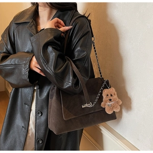 Detailansicht der braunen Wildledertasche mit Metallkette und süßem Teddybär-Anhänger