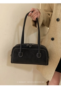 Detail of retro black suede handbag with white stitching and dual zipper closure system