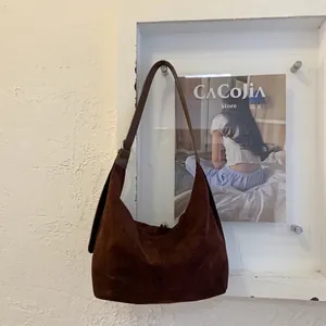 Dettaglio della borsa hobo in pelle scamosciata marrone scuro con tracolla larga e fibbia