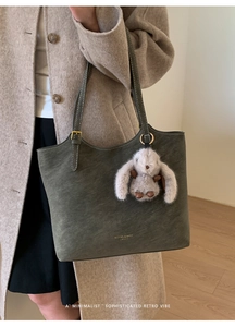 Détail du sac cabas en daim vert olive avec boucle dorée et breloque lapin en peluche