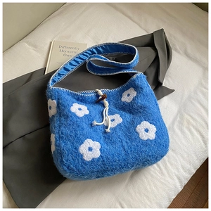 Close-up of blue plush tote bag with white flower embroidery and wooden button closure