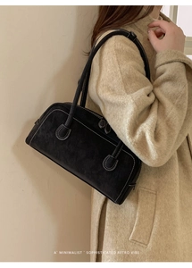 Close-up of retro black suede shoulder bag with white contrast stitching and long straps