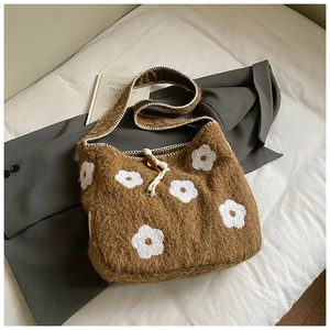 Detail of plush floral embroidery shoulder bag with toggle closure on fabric background