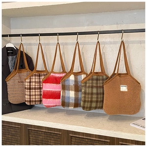 Detailed display of assorted plaid and wool tote bags hanging on a display rack