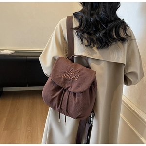 Close-up of brown drawstring backpack featuring 'YOU JIBEAR!' embroidery and premium fabric