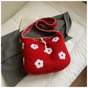 Close-up of red plush floral shoulder bag with white flower embroidery and wooden drawstring