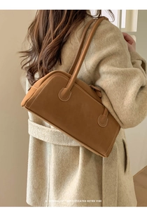 Detail of brown faux suede shoulder bag with contrast stitching on a wool coat