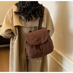 Detailed view of brown fabric backpack with YOU BEAR embroidery and drawstring closure