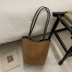 Detail view of the brown suede bucket bag with leather strap in a minimalist home setting