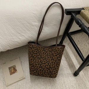 Detailed close-up of leopard print bucket bag with brown straps in home setting