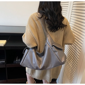 Vue détaillée d'un grand sac hobo en cuir gris foncé porté par un mannequin de dos