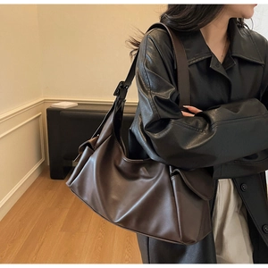 Détail d'un grand sac à bandoulière en cuir marron foncé avec poche latérale à rabat