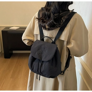 Detailed back view of a black nylon drawstring backpack with letter embroidery