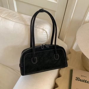 Detail of black faux suede handbag showing white contrast stitching and double zippers