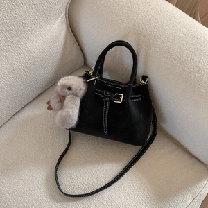 Detail of matte black tote bag featuring contrast stitching and a grey rabbit plush charm
