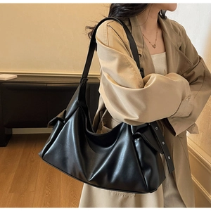 Vue détaillée d'un grand sac cabas noir en cuir avec plis et œillets argentés sur la bandoulière