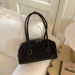 Detail of vintage brown suede handbag with white contrast stitching on a beige sofa