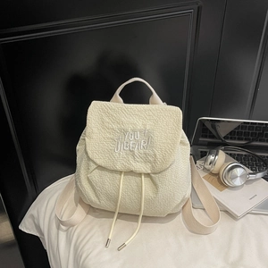 Detail of cream-white drawstring backpack with bubble texture fabric and embroidery
