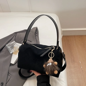 Detail der schwarzen Wildleder-Bostontasche mit verspieltem braunem Pelzmonster-Anhänger