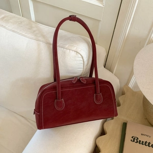 Macro detail of dark red faux suede shoulder bag with contrast stitching and double zippers