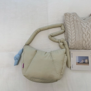Primo piano della borsa trapuntata verde chiaro con charm a nodo blu su tessuto testurizzato