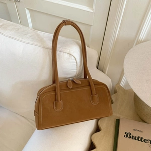 Detailed view of brown faux suede shoulder bag with contrast white stitching and dual zippers