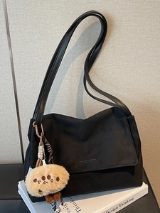 Chic black matte shoulder bag with chain strap and cute plush charm on art books