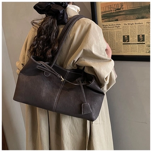 Close-up of deep brown leather tote bag featuring contrast white stitching and strap detail