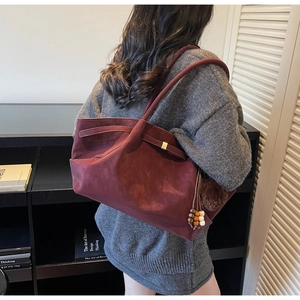 Close-up of burgundy suede tote bag featuring retro wooden beads and fur ball pendant