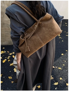 Detail of a brown suede tote bag with white contrast stitching and long shoulder straps
