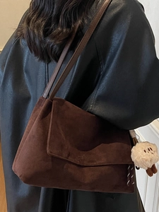 Minimalist dark brown suede shoulder bag with chain strap and cute sheep charm on model