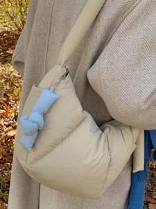 Borsa a mano trapuntata beige stile piumino con ciondolo blu e tracolla larga