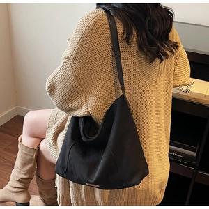 Close-up of black canvas hobo bag with high-quality metal logo patch and durable wide strap