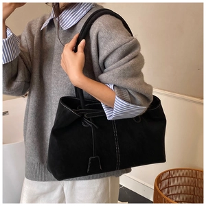 Detail of black suede tote bag featuring white contrast stitching and side drawstring