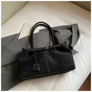 Detail of a black minimalist tote bag with contrast white stitching and gold buckle closure