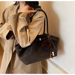 Detailed view of coffee suede tote bag with plush ball and beads decoration
