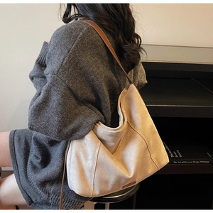 Detail of minimalist beige suede tote bag featuring contrast stitching and leather strap
