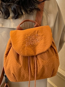 Orange waffle texture drawstring backpack with letter embroidery shown on model