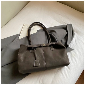 Detail of dark grey tote bag showing leather texture, white stitching, and golden hardware
