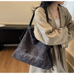 Detail of leopard print tote bag featuring Gugigugi embroidery and black leather straps