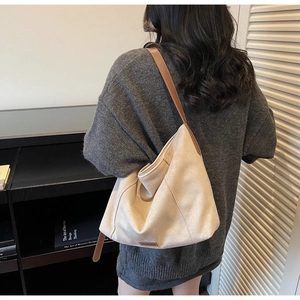 Detail of beige suede tote bag with brown leather straps worn by a model in casual style
