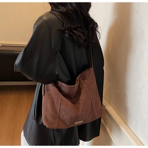Close-up of brown suede tote bag with contrast stitching and metallic logo detailing