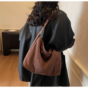 Detailed view of dark brown suede hobo bag with visible stitching and adjustable strap