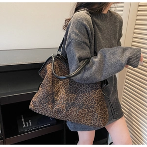 Macro view of leopard print tote bag featuring black embroidery and faux leather handles