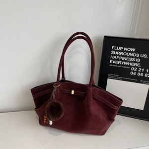 Detail view of maroon faux suede tote bag featuring a plush charm and metal buckle design