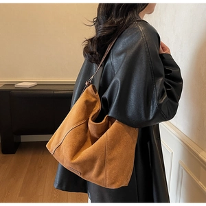 Detail of the soft texture and draping effect of a large brown suede tote bag