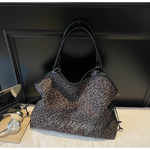 Detail of leopard print tote bag with stylish grey embroidery and black leather handles