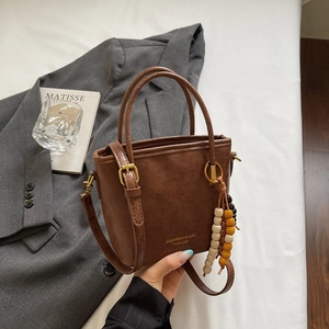 Dettaglio della borsa a secchiello marrone vintage con fibbie d'oro e ciondoli in legno